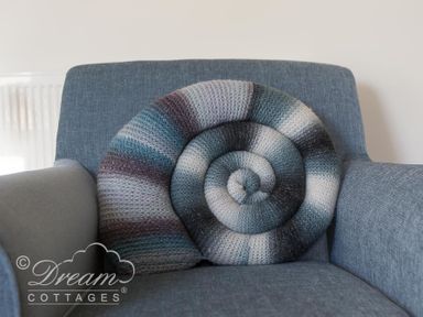 A knitted spiral cushion on a blue armchair at Ammonite Cottage Fortuneswell Portland