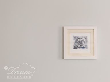 A framed picture of a fossil on a light grey wall at Ammonite Cottage in Fortuneswell Portland
