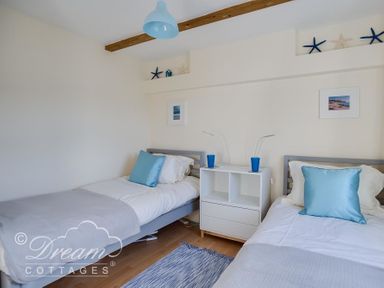 A bedroom with two single beds and a white bedside table between them at Ammonite Cottage Fortuneswell Portland