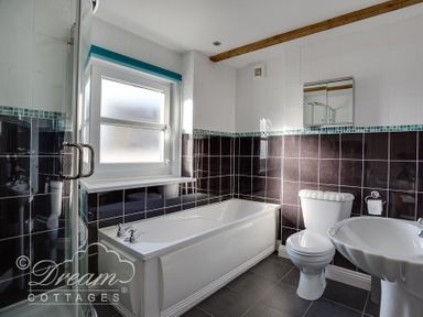 A bathroom with a bathtub toilet sink and shower cubicle at Ammonite Cottage in Fortuneswell Portland