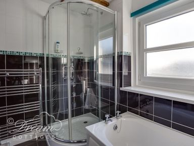 A bathroom with a corner shower enclosure bathtub and window at Ammonite Cottage Fortuneswell Portland