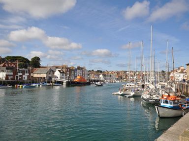A harbor with multiple sailboats and motorboats docked along the waterfront with buildings in the background at Brewers Quay Harbour