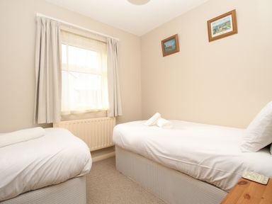 A bedroom with two single beds a window with curtains and two framed pictures on the wall at Anvil House Brewers Quay Harbour