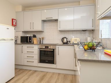 A kitchen with white cabinets appliances countertop fruit basket and wooden floor at Anvil House in Brewers Quay Harbour