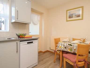 A kitchen with a dining table set with plates and glasses a fruit bowl on the counter and a framed picture on the wall at Anvil House Brewers Quay Harbour