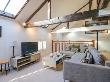 A living room with a gray sectional sofa coffee table tv and wooden beams at Barley Mews Brewers Quay Harbour