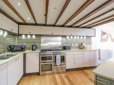 A kitchen with wooden floor and ceiling beams stainless steel oven and beige cabinets at Barley Mews Brewers Quay Harbour