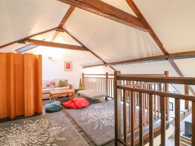An attic lounge area with wooden beams a sofa a coffee table cushions and rugs at Barley Mews in Brewers Quay Harbour