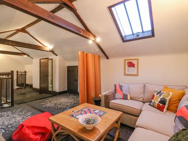 A living area with a beige sectional sofa with colorful cushions a wooden coffee table a red bean bag and exposed wooden ceiling beams at Barley Mews Brewers Quay Harbour