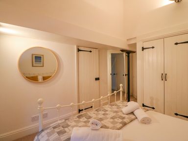 A bedroom with a bed folded towels a round mirror on the wall and doors at Barley Mews in Brewers Quay Harbour