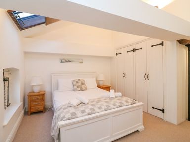A bedroom with a double bed bedside tables lamps and built in wardrobes at Barley Mews in Brewers Quay Harbour