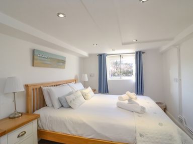 A bedroom with a wooden bed and white bedding with rolled towels on top at Barley Mews in Brewers Quay Harbour