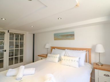 A bedroom with a double bed two bedside tables lamps and a painting above the bed at Barley Mews in Brewers Quay Harbour