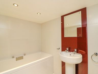 A bathroom with a bathtub and a pedestal sink with a mirror at Barley Mews in Brewers Quay Harbour