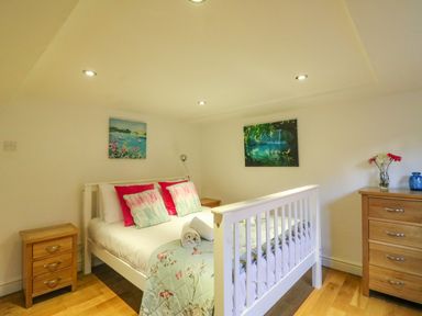 A bedroom with a white bed framed by two wooden bedside tables and a wooden chest of drawers at Barley Mews in Brewers Quay Harbour