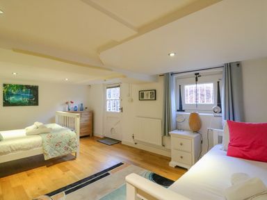 A bedroom with two beds a wooden dresser a bedside table and windows at Barley Mews Brewers Quay Harbour