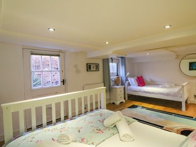 A bedroom with two beds a window and a door at Barley Mews in Brewers Quay Harbour