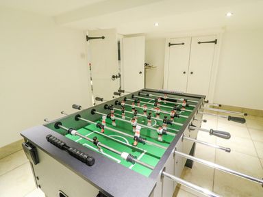 A room with a foosball table on a tiled floor and white doors at Barley Mews Brewers Quay Harbour