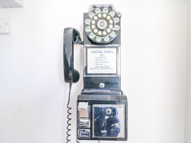 A black vintage rotary payphone mounted on a white wall at Barley Mews Brewers Quay Harbour