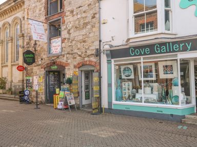 A street view showing Londis Harbour Stores and Cove Gallery with art and crafts on display at Barley Mews in Brewers Quay Harbour