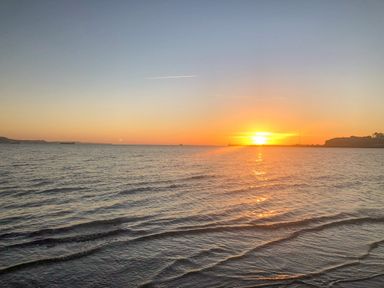 A sunset over the ocean with a clear sky and gentle waves at Barley Mews in Brewers Quay Harbour