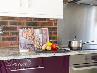 A kitchen countertop with vegetables a cookbook a saucepan and a spice container at Baytree Lodge in Osmington