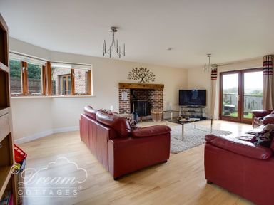 A living room with red leather sofas a brick fireplace and a TV at Baytree Lodge in Osmington