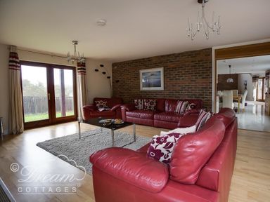 A living room with red leather sofas and a glass coffee table on a rug at Baytree Lodge in Osmington