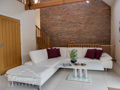 A living room with a white sectional sofa and a glass coffee table with a plant on it at Baytree Lodge in Osmington