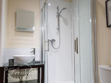 A bathroom with a glass shower enclosure a round basin on a black countertop and a toilet at Baytree Lodge in Osmington