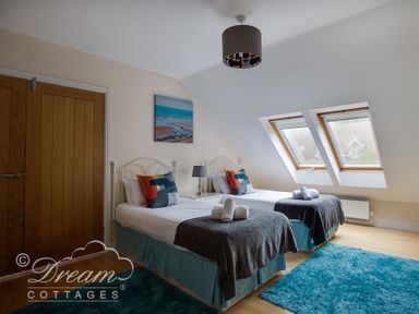 A bedroom with two single beds blue rugs and skylight windows at Baytree Lodge in Osmington