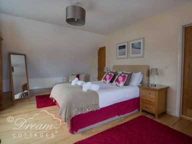A bedroom with a double bed bedside tables a mirror an armchair and a rug at Baytree Lodge in Osmington