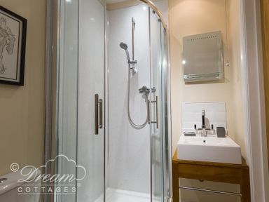 A bathroom with a corner shower enclosure and a sink with a mirror above at Baytree Lodge in Osmington