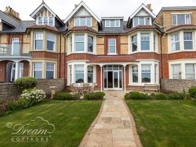 Back garden with a table set and chairs at a brick house with bay windows at Beach View Apartment 2 in Greenhill