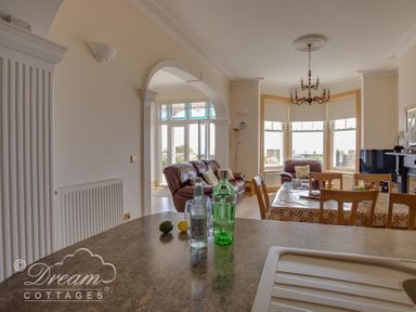 A living room with leather sofas a dining table and large bay windows at Beach View Apartment 2 in Greenhill