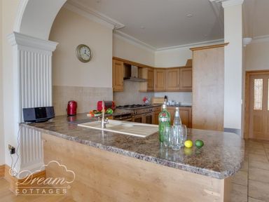 A kitchen with a countertop sink stove and wooden cabinets at Beach View Apartment 2 in Greenhill