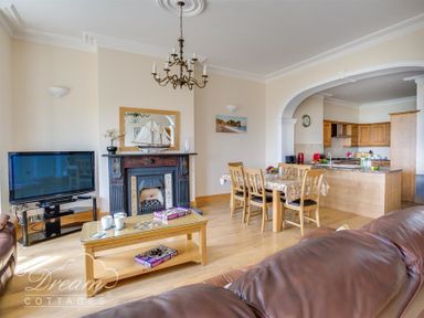 An open living room and kitchen area with a fireplace television dining table and chairs at Beach View Apartment 2 in Greenhill