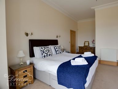 A bedroom with a double bed with white bedding and blue throw at Beach View Apartment 2 in Greenhill