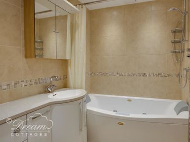 A bathroom with a bathtub a shower a sink with a countertop and a mirrored cabinet at Beach View Apartment 2 in Greenhill