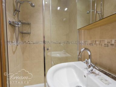 A bathroom with a shower cubicle and a sink with a faucet at Beach View Apartment 2 in Greenhill
