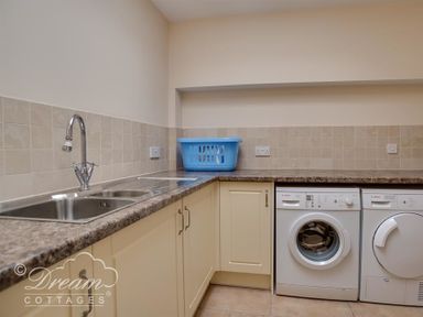 A laundry room with a sink a blue laundry basket a washing machine and a dryer at Beach View Apartment 2 in Greenhill