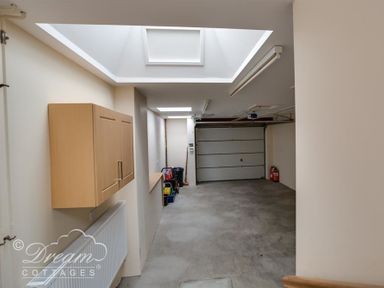 An empty garage with a closed door ceiling lights a wooden cabinet a radiator and some cleaning supplies at Beach View Apartment 2 in Greenhill