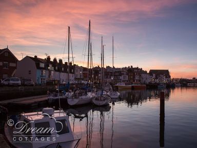 A harbor with boats docked near houses at sunset at Beach View Apartment 2 in Greenhill