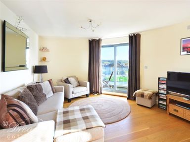 A living room with a sofa armchair TV and sliding glass doors at The Boardwalk in West Bay