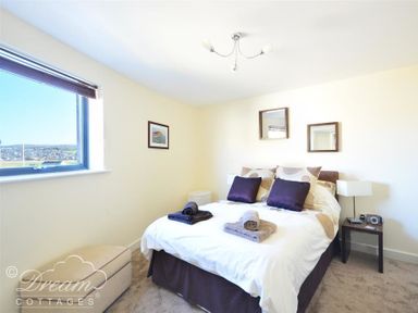 A bedroom with a bed with pillows and towels next to a window and bedside tables at The Boardwalk in West Bay