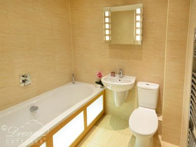 A bathroom with a bathtub sink toilet and mirror at The Boardwalk in West Bay