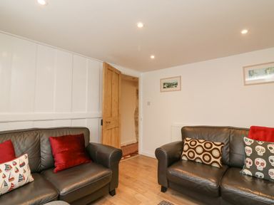 A sitting room with two leather sofas and patterned cushions at Bowman's Cottage in Wakeham Portland