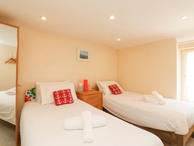 A bedroom with two single beds a wooden nightstand and a large mirror at Bowman's Cottage in Wakeham Portland