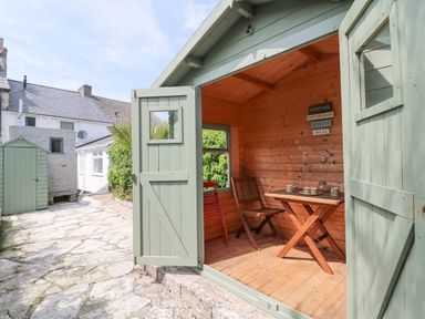 An open wooden garden shed with a table and two chairs inside at Bowmans Cottage in Wakeham Portland