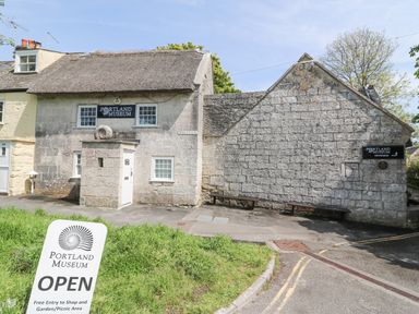 Stone buildings with thatched roof and signs for Portland Museum in Wakeham Portland
